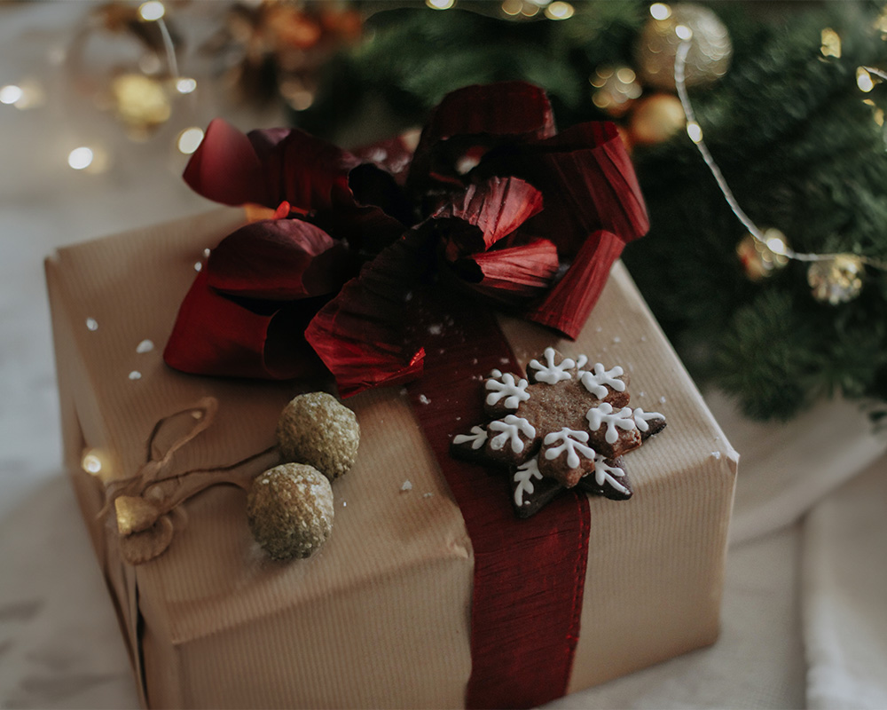 Regalo de Navidad envuelto en papel, atado con un lazo y decorado con una galleta.