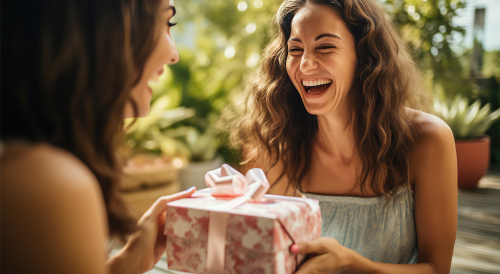 Mujer sonriente entrega un regalo a una amiga.