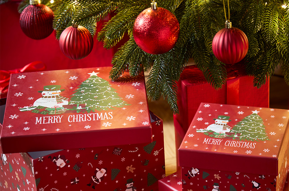 Cajas de regalo con motivos navideños junto al árbol de Navidad.