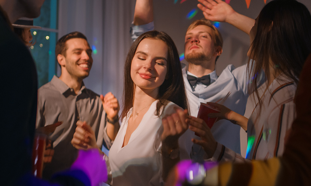 Un grupo de personas bailando en una fiesta, entre las que se encuentra una mujer disfrutando de la música.